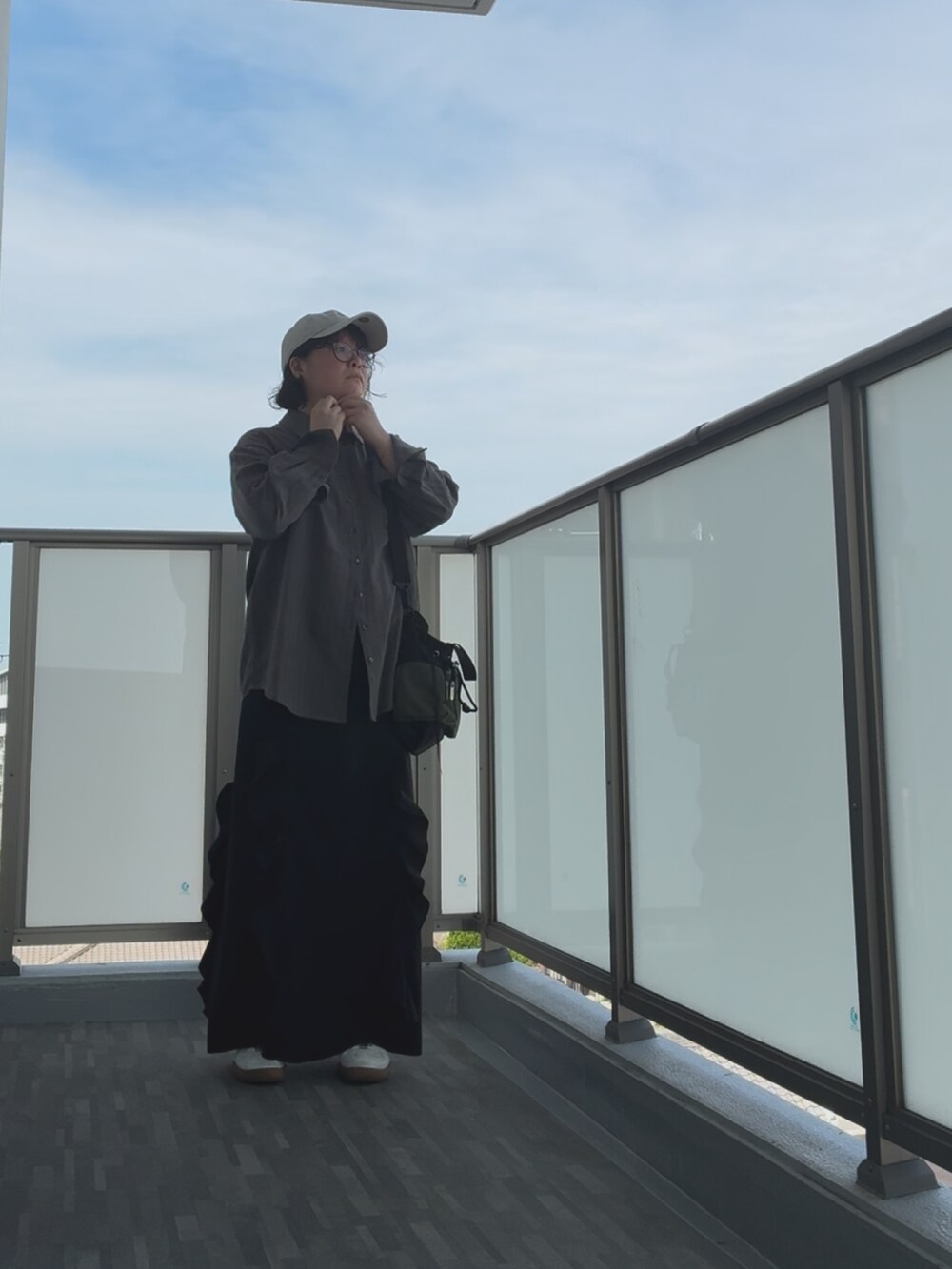 ブラック系のショルダーバッグ、シルバー系のスニーカー、ブラック系のスカートを着用したレディースの秋コーディネートの3枚目の写真