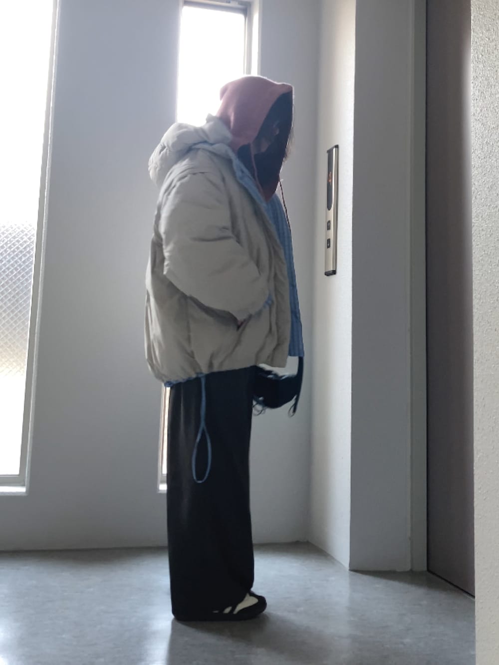 ブルー系のダウンジャケット/コート、ホワイト系のニット/セーター、ブラック系のバッグを着用したレディースの冬コーディネートの3枚目の写真