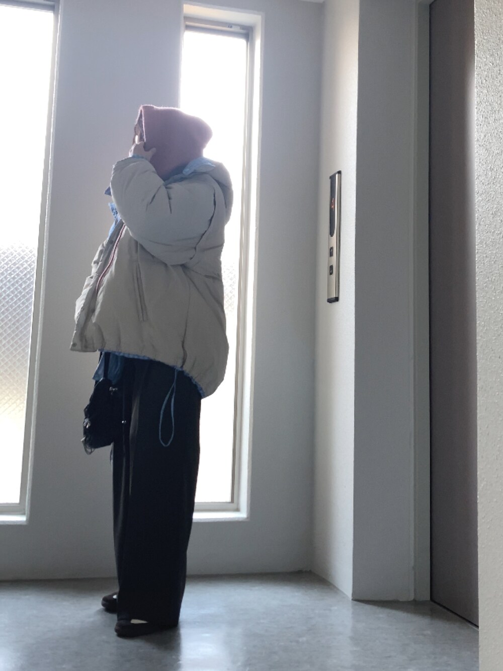 ブルー系のダウンジャケット/コート、ホワイト系のニット/セーター、ブラック系のバッグを着用したレディースの冬コーディネートの2枚目の写真