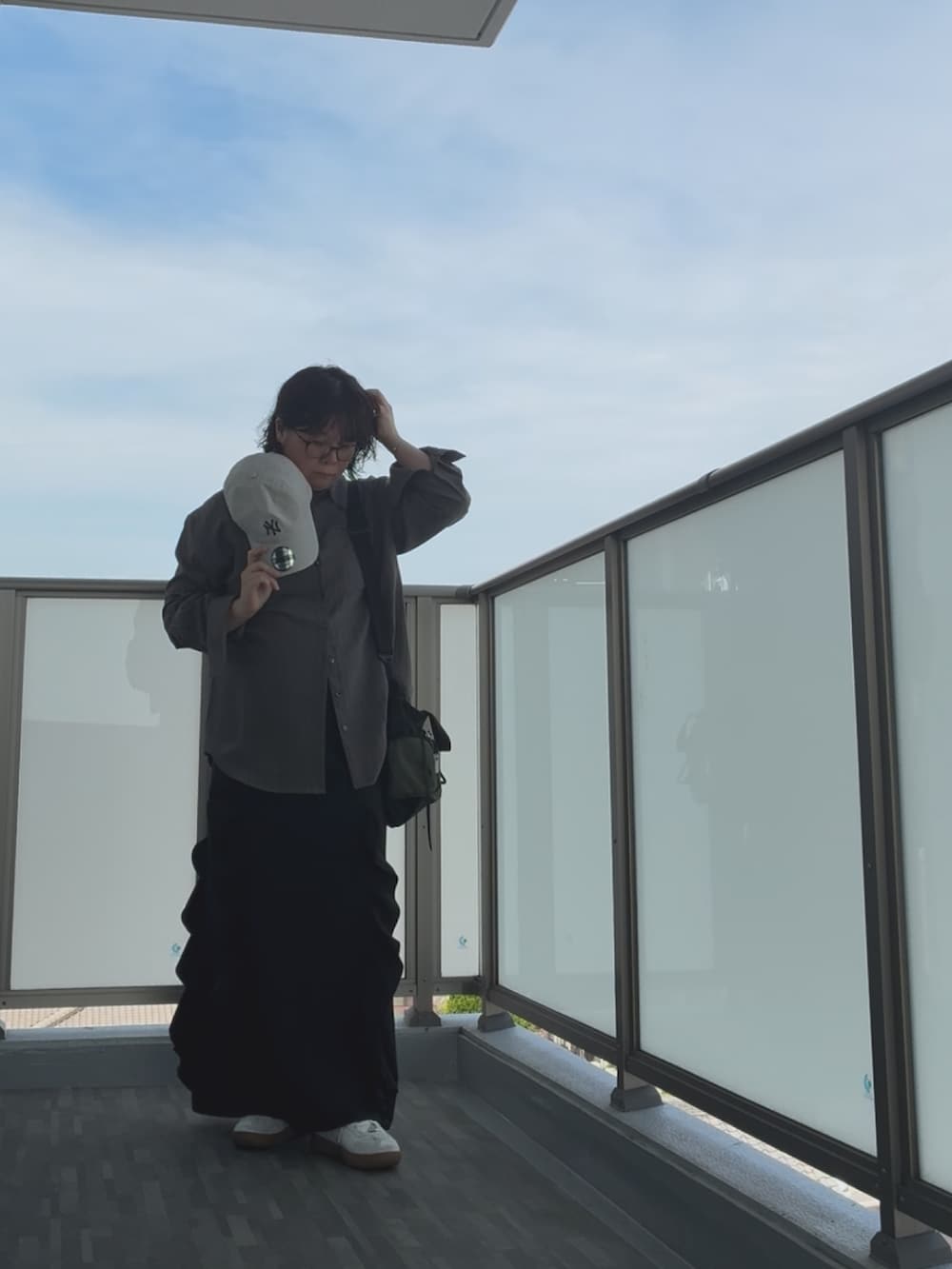 ブラック系のショルダーバッグ、シルバー系のスニーカー、ブラック系のスカートを着用したレディースの秋コーディネートの5枚目の写真