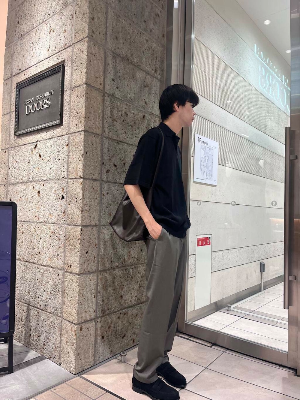 ブラック系のポロシャツ、ブラウン系のショルダーバッグ、グリーン系のスーツパンツを着用したメンズの夏コーディネートの3枚目の写真