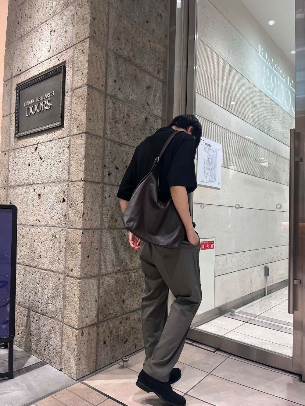 ブラック系のポロシャツ、ブラウン系のショルダーバッグ、グリーン系のスーツパンツを着用したメンズの夏コーディネートの2枚目の写真