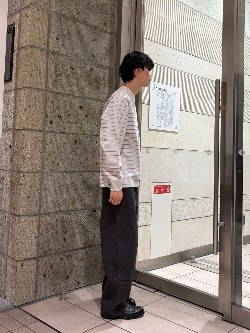 レッド系のTシャツ/カットソー、ブラック系のドレスシューズ、グレー系のその他パンツを着用したメンズの冬コーディネートの3枚目の写真