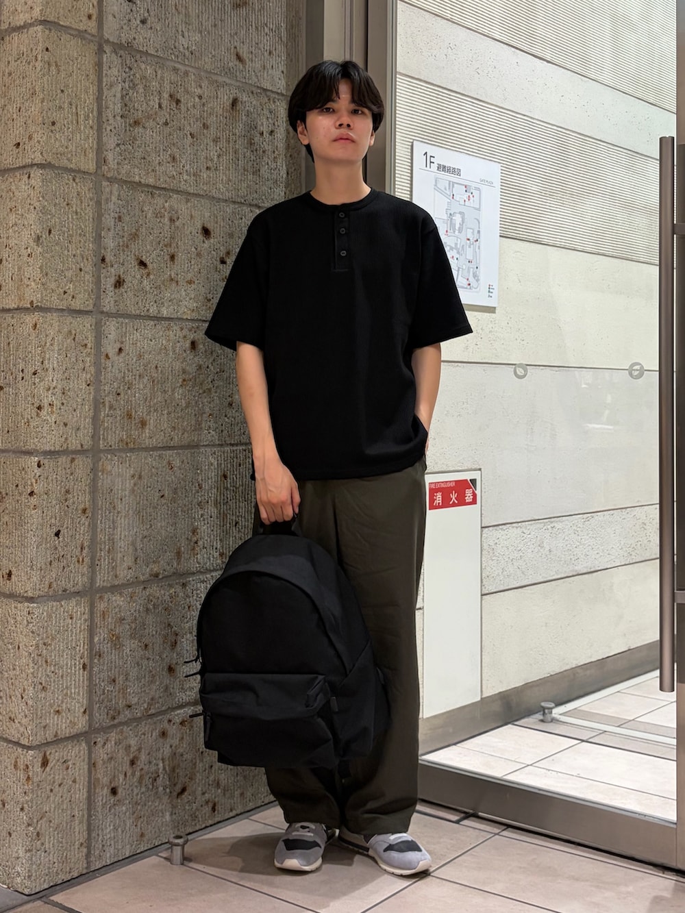 ブラック系のTシャツ/カットソー、グリーン系のその他パンツ、ブラック系のバックパック/リュックを着用したメンズの夏コーディネートの2枚目の写真