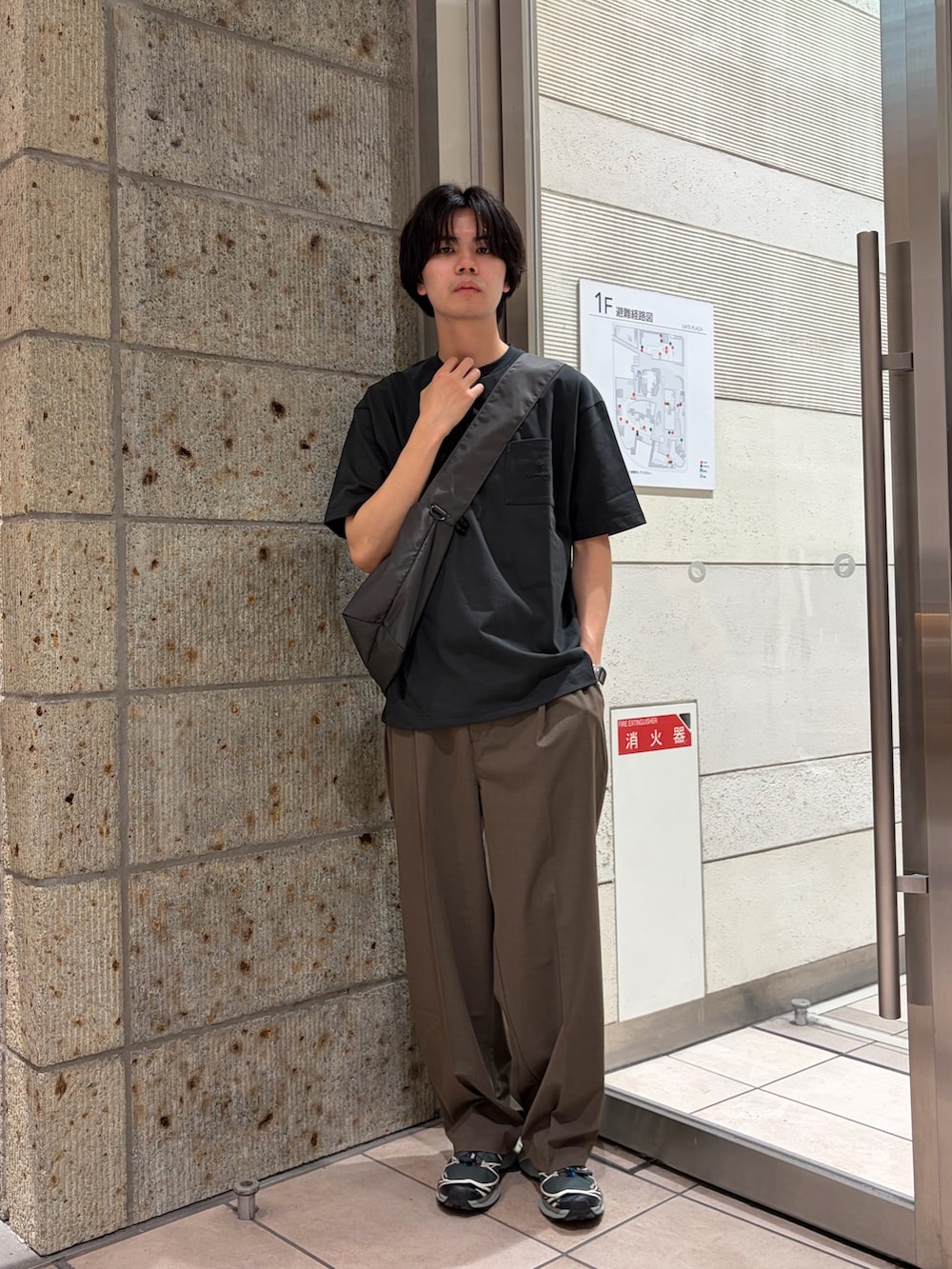 グレー系のTシャツ/カットソー、グレー系のショルダーバッグ、ブラック系のスニーカーを着用したメンズの春コーディネートの3枚目の写真