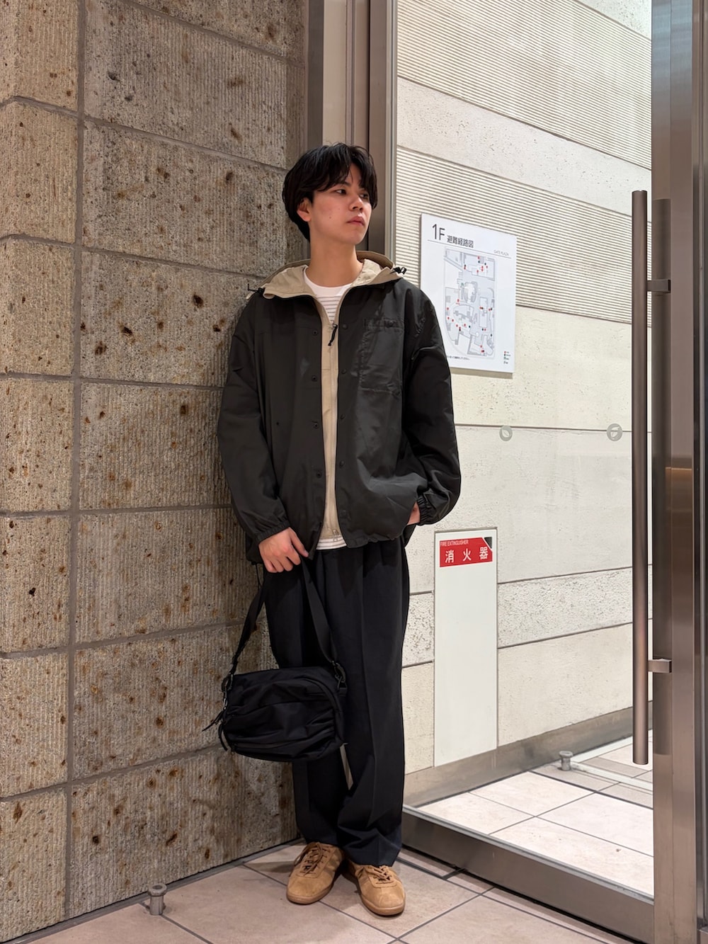 ベージュ系のマウンテンパーカー、ブラック系のその他アウター、ホワイト系のTシャツ/カットソーを着用したメンズの春コーディネートの2枚目の写真