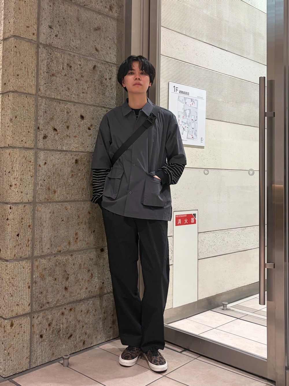 ブラウン系のスニーカー、グレー系のシャツ/ブラウス、ブラック系のショルダーバッグを着用したメンズの春コーディネートの2枚目の写真