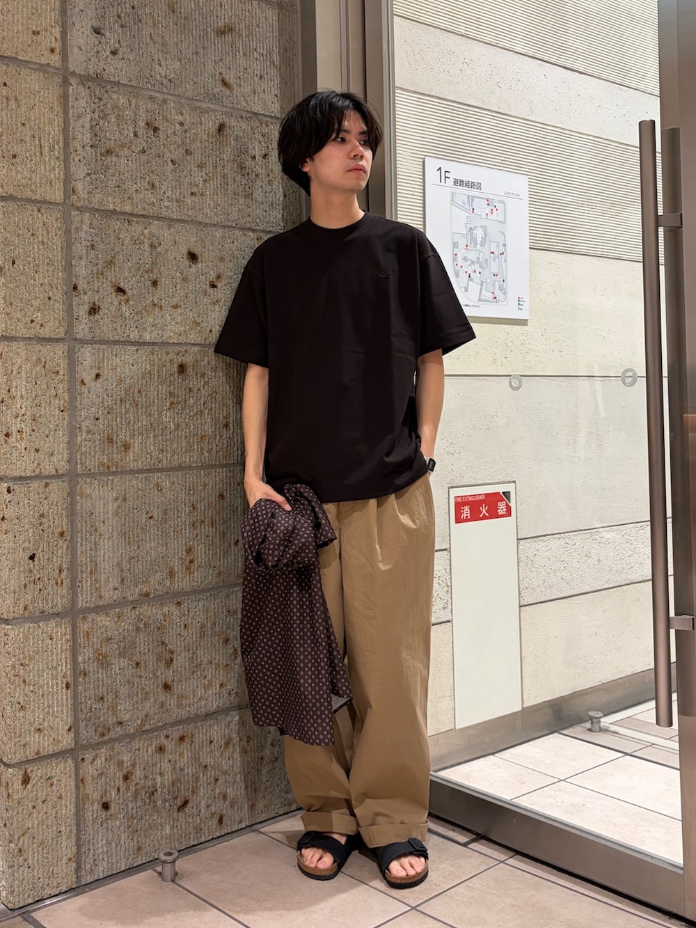 ブラウン系のTシャツ/カットソー、ベージュ系のその他パンツ、ブラック系のサンダルを着用したメンズの春コーディネートの2枚目の写真