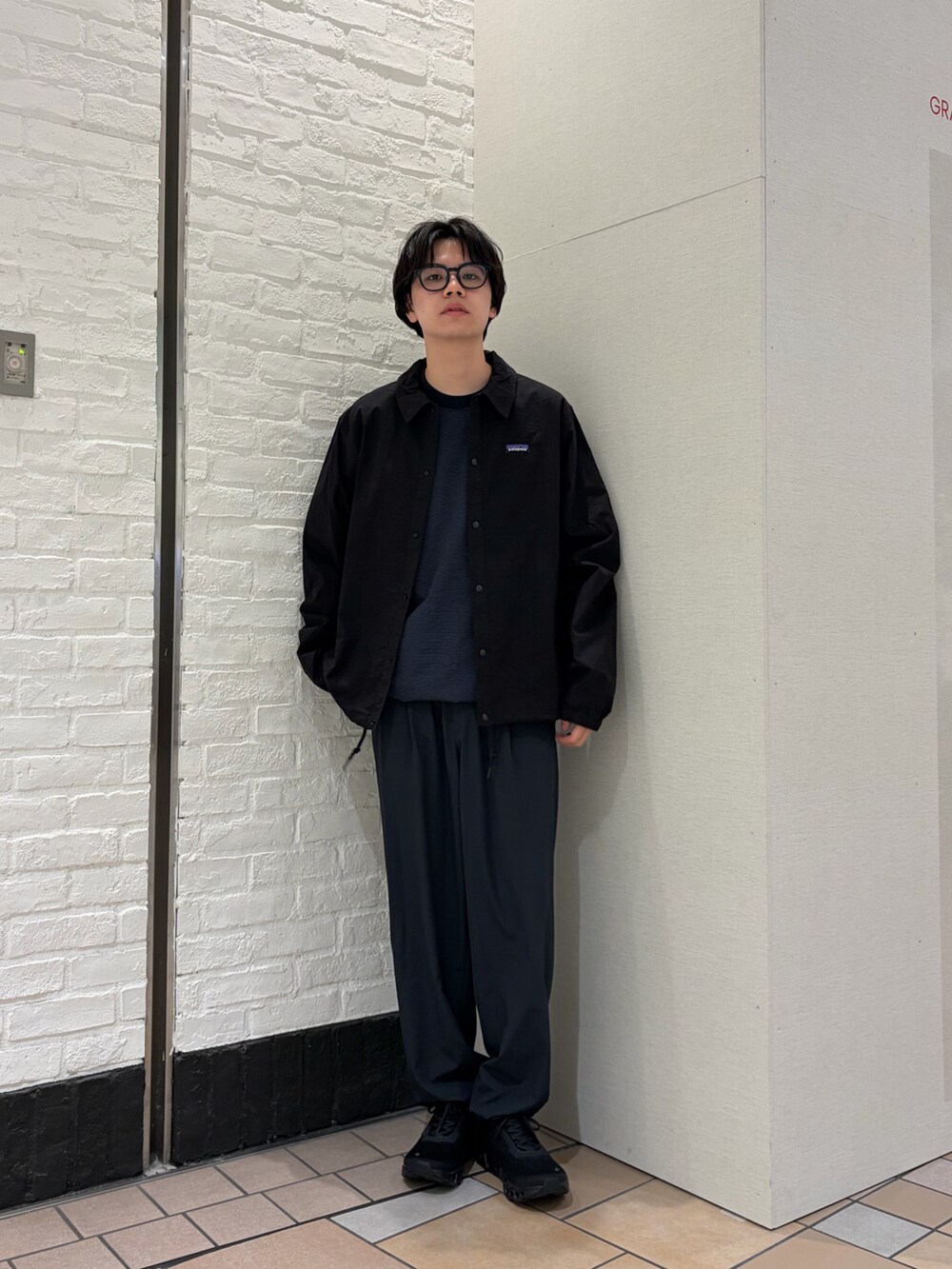 ブラック系のカバーオール、ブルー系のTシャツ/カットソー、ブラック系のスニーカーを着用したメンズの春コーディネートの2枚目の写真