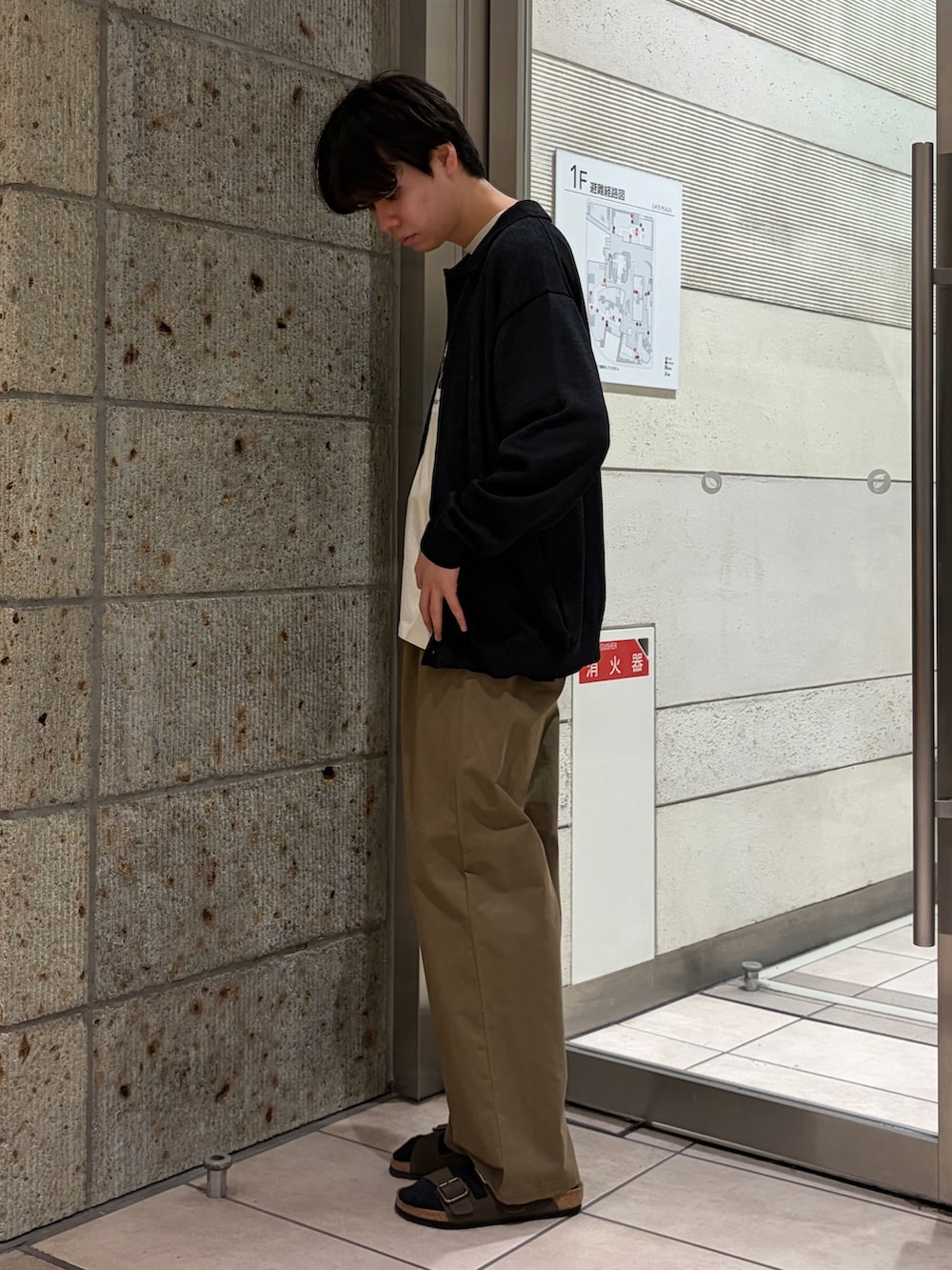 ブラック系のカーディガン/ボレロ、ホワイト系のTシャツ/カットソー、ベージュ系のチノパンツを着用したメンズの夏コーディネートの3枚目の写真