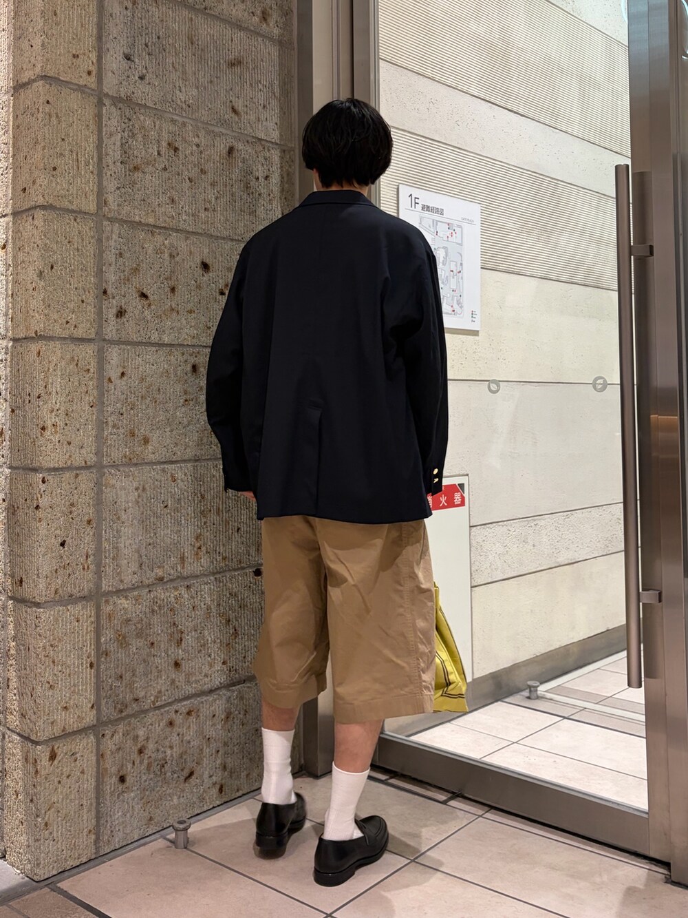 ベージュ系のその他パンツ、イエロー系のトートバッグ、ブラック系のドレスシューズを着用したメンズの春コーディネートの4枚目の写真