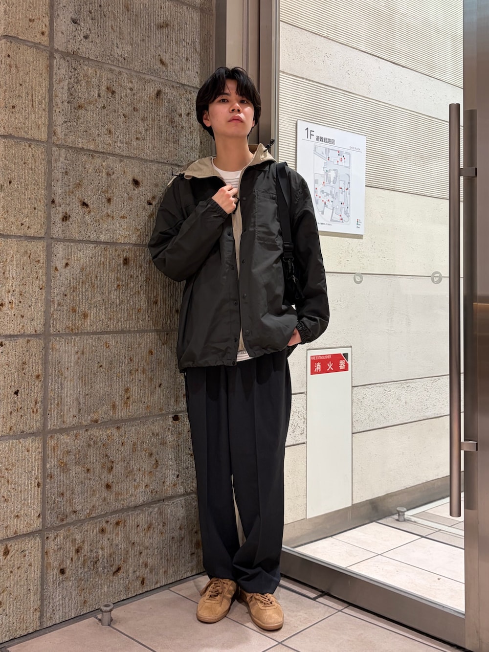 ベージュ系のマウンテンパーカー、ブラック系のその他アウター、ホワイト系のTシャツ/カットソーを着用したメンズの春コーディネートの6枚目の写真