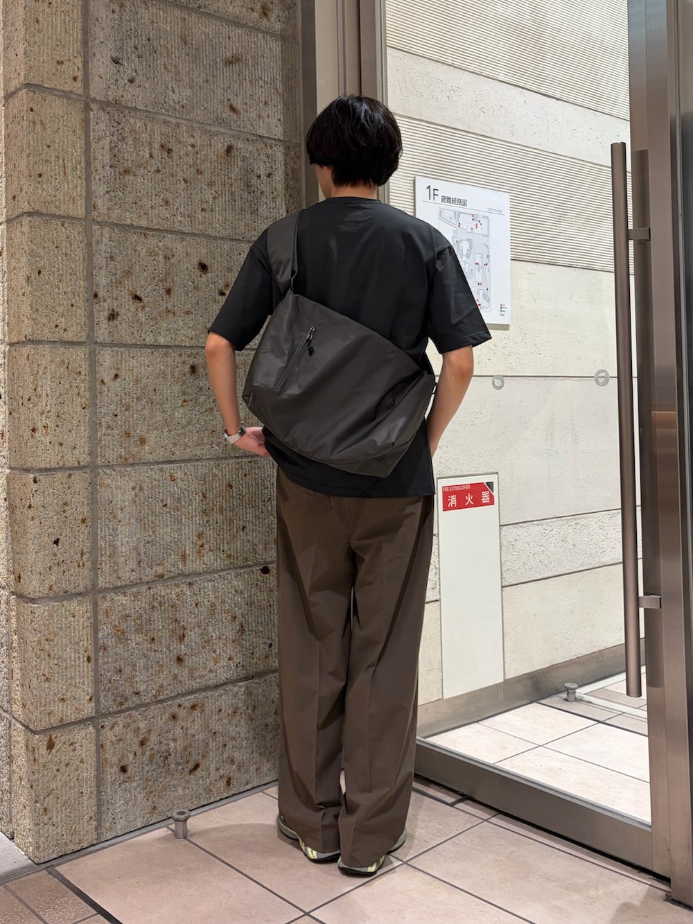 グレー系のTシャツ/カットソー、グレー系のショルダーバッグ、ブラック系のスニーカーを着用したメンズの春コーディネートの5枚目の写真