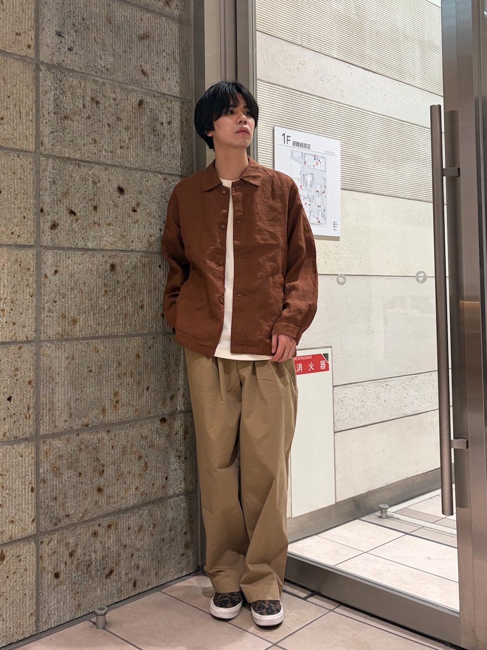 ブラウン系のその他アウター、ブラウン系のスニーカー、ベージュ系のTシャツ/カットソーを着用したメンズの春コーディネートの2枚目の写真