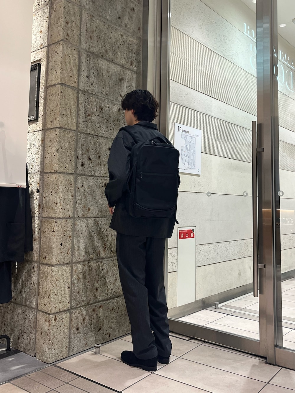 ブラック系のビジネスバッグ、グレー系のTシャツ/カットソー、ブラック系のドレスシューズを着用したメンズの秋コーディネートの3枚目の写真