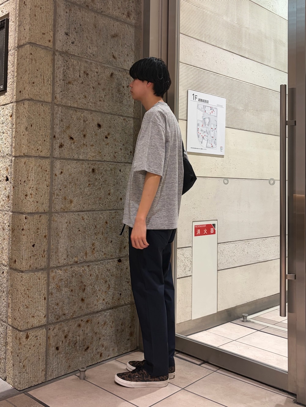 ブラウン系のスニーカー、ブラック系のショルダーバッグ、グレー系のTシャツ/カットソーを着用したメンズの春コーディネートの3枚目の写真