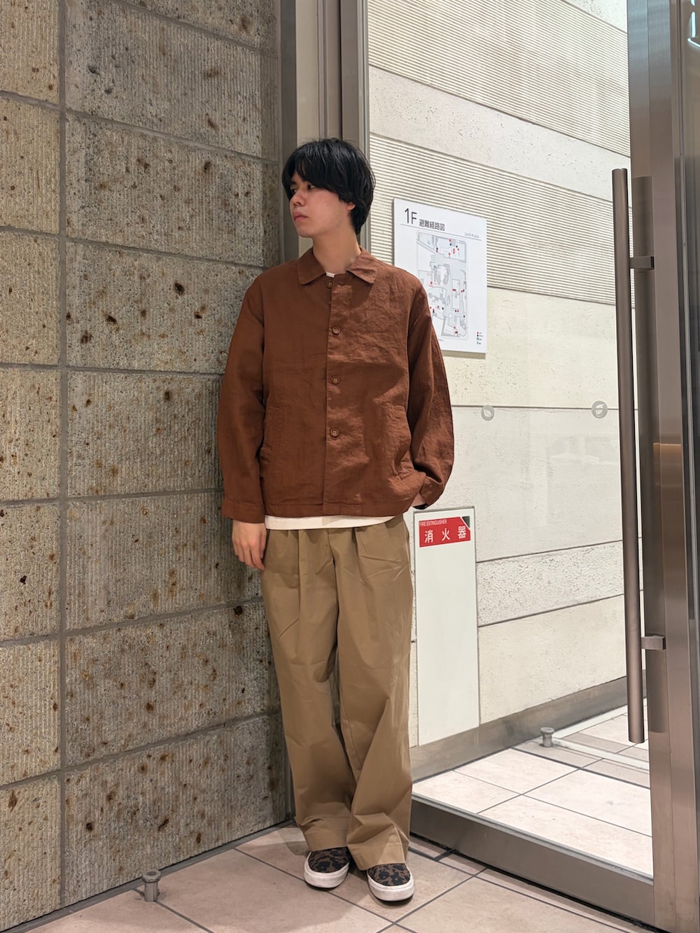 ブラウン系のその他アウター、ブラウン系のスニーカー、ベージュ系のTシャツ/カットソーを着用したメンズの春コーディネートの3枚目の写真