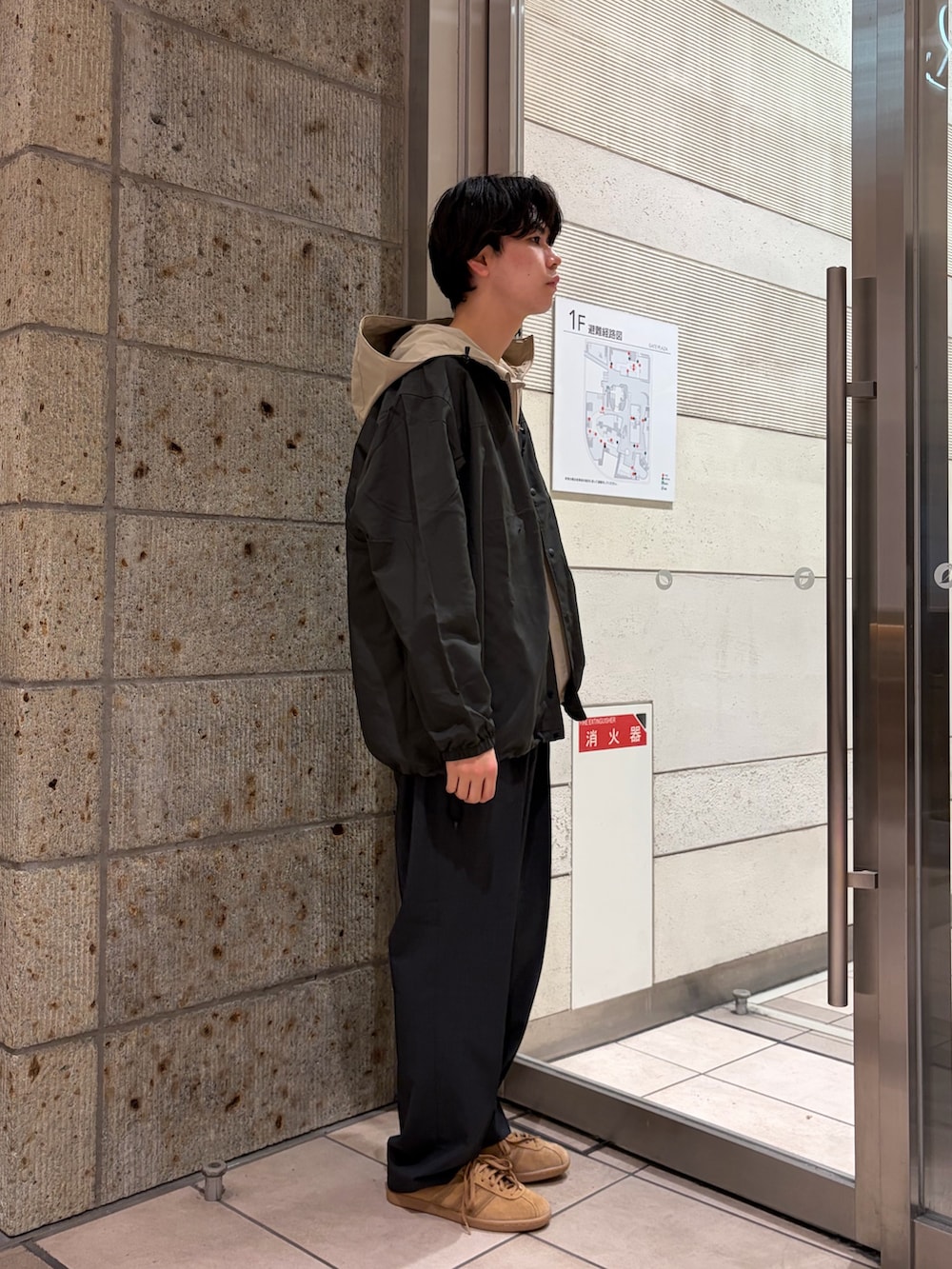 ベージュ系のマウンテンパーカー、ブラック系のその他アウター、ホワイト系のTシャツ/カットソーを着用したメンズの春コーディネートの5枚目の写真