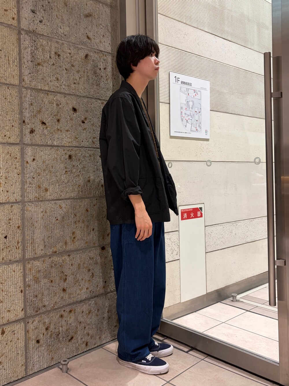 ブラック系のその他アウター、ブラウン系のニット/セーター、ブルー系のデニムパンツを着用したメンズの春コーディネートの6枚目の写真