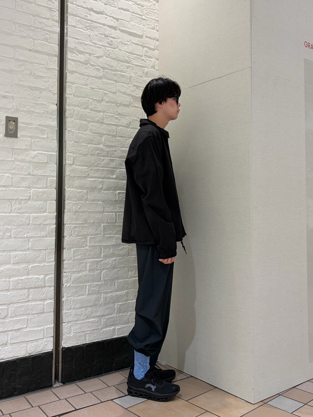 ブラック系のカバーオール、ブルー系のTシャツ/カットソー、ブラック系のスニーカーを着用したメンズの春コーディネートの5枚目の写真