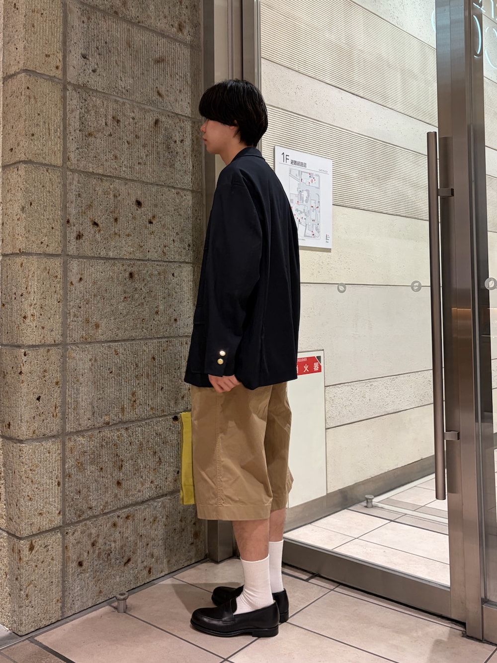 ベージュ系のその他パンツ、イエロー系のトートバッグ、ブラック系のドレスシューズを着用したメンズの春コーディネートの3枚目の写真