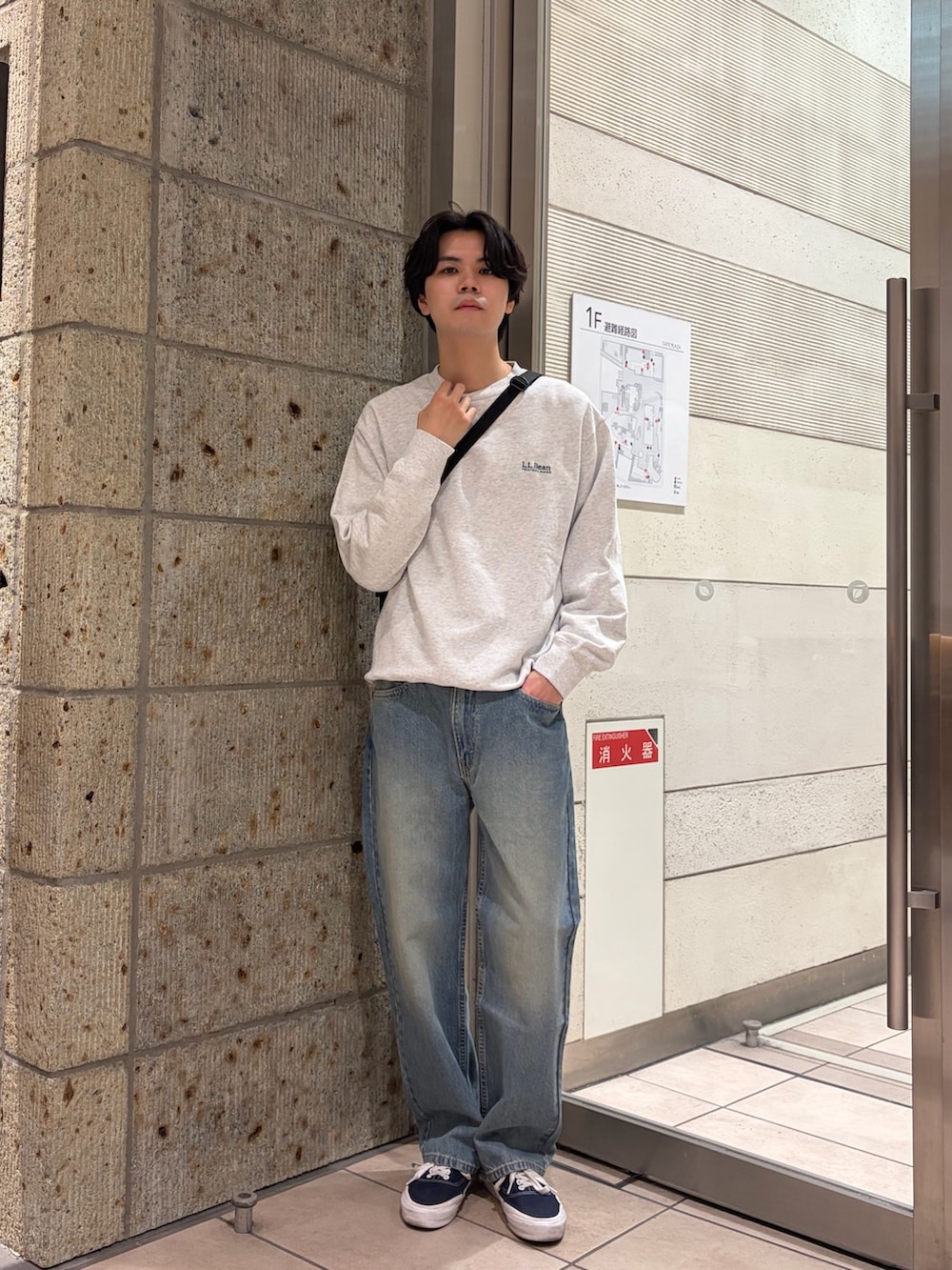 グレー系のTシャツ/カットソー、ブラック系のショルダーバッグ、ブルー系のデニムパンツを着用したメンズの冬コーディネートの2枚目の写真