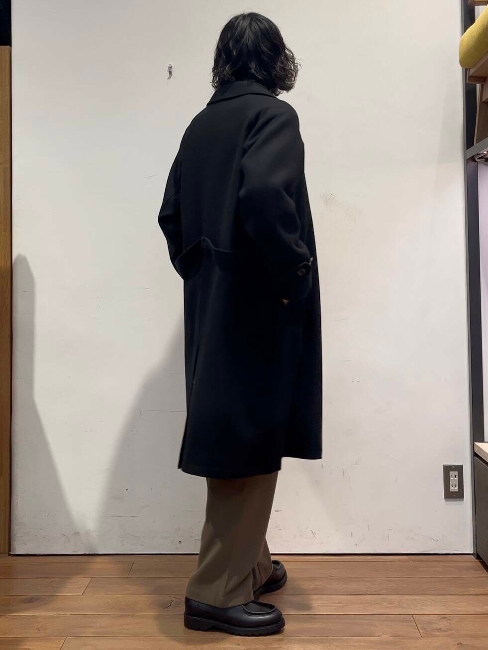 ベージュ系のTシャツ/カットソー、ブラック系のステンカラーコート、グリーン系のその他パンツを着用したメンズの冬コーディネートの4枚目の写真