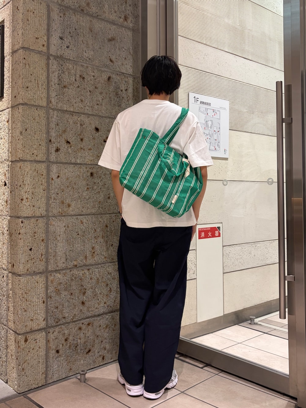 グリーン系のトートバッグ、グレー系のスニーカー、ブルー系のその他パンツを着用したメンズの春コーディネートの3枚目の写真