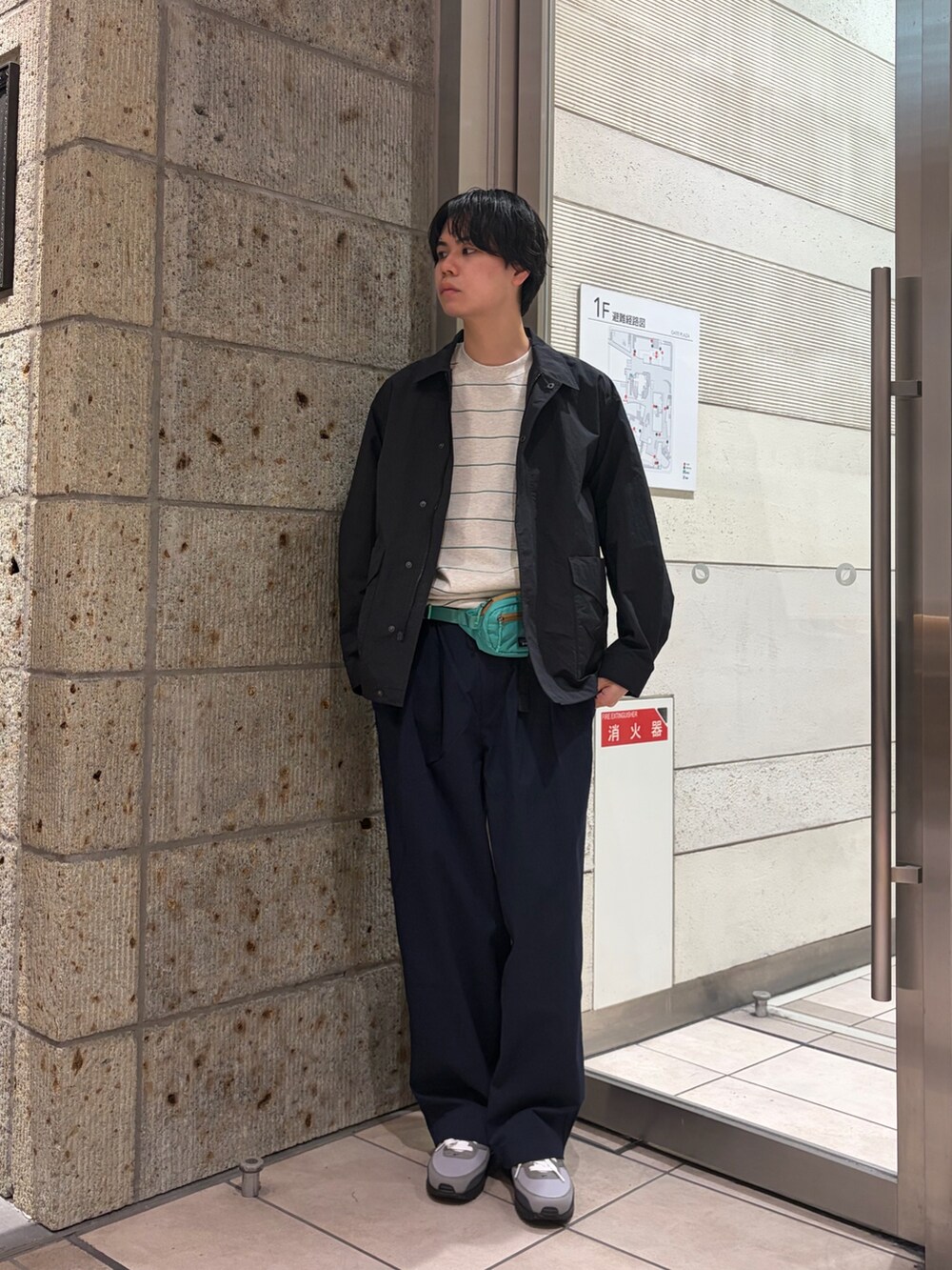 ブラック系のナイロンジャケット、ブルー系のその他パンツ、グリーン系のTシャツ/カットソーを着用したメンズの春コーディネートの2枚目の写真