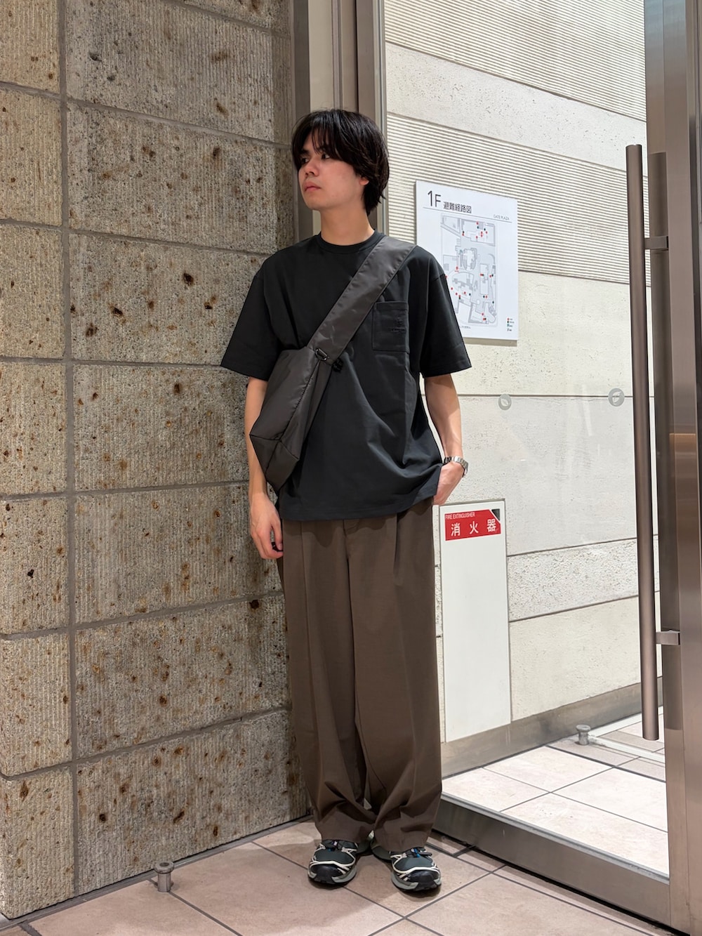 グレー系のTシャツ/カットソー、グレー系のショルダーバッグ、ブラック系のスニーカーを着用したメンズの春コーディネートの2枚目の写真