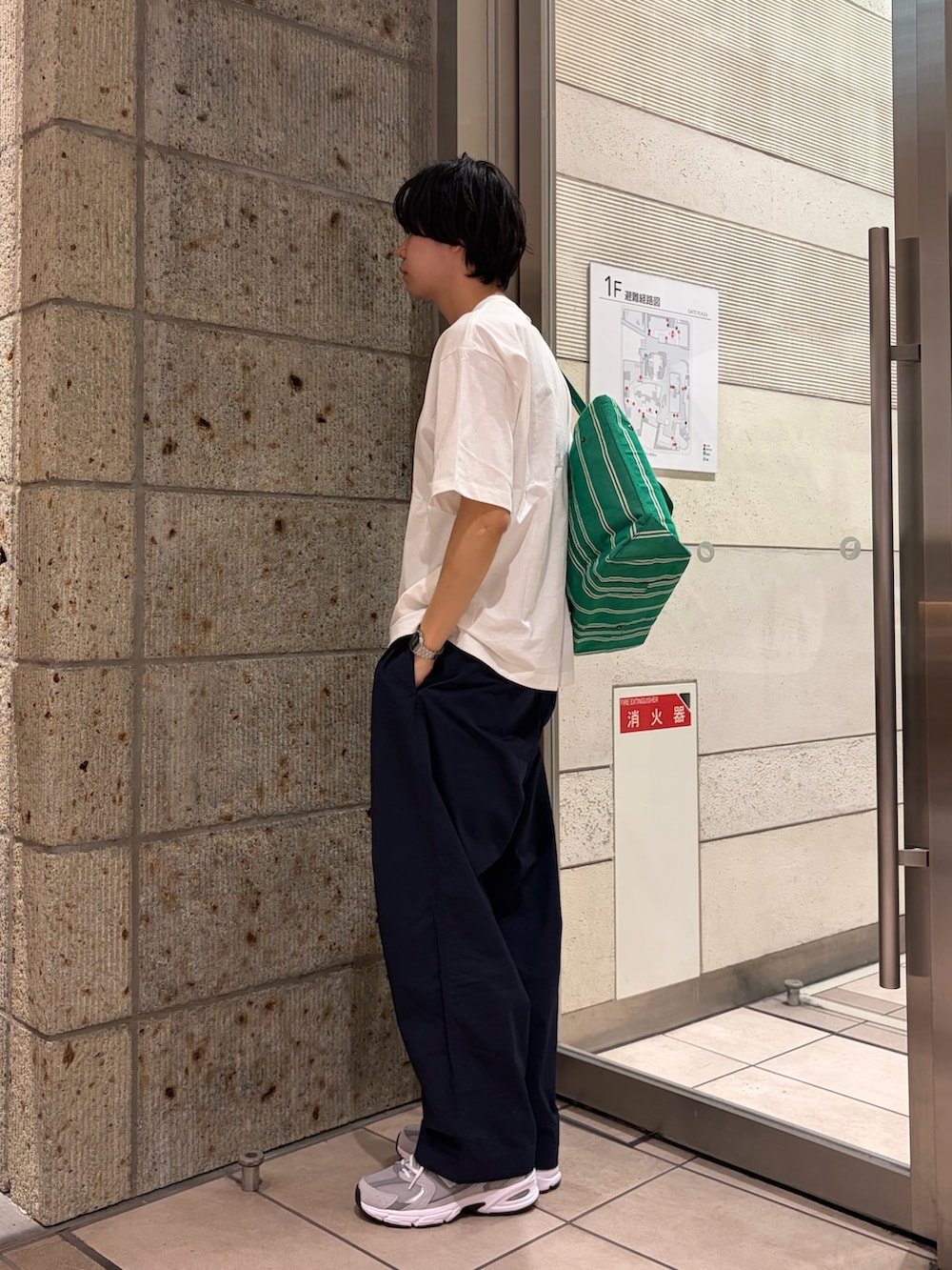 グリーン系のトートバッグ、グレー系のスニーカー、ブルー系のその他パンツを着用したメンズの春コーディネートの2枚目の写真