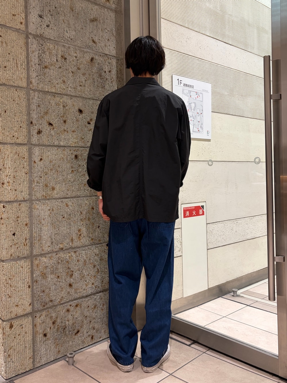 ブラック系のその他アウター、ブラウン系のニット/セーター、ブルー系のデニムパンツを着用したメンズの春コーディネートの5枚目の写真