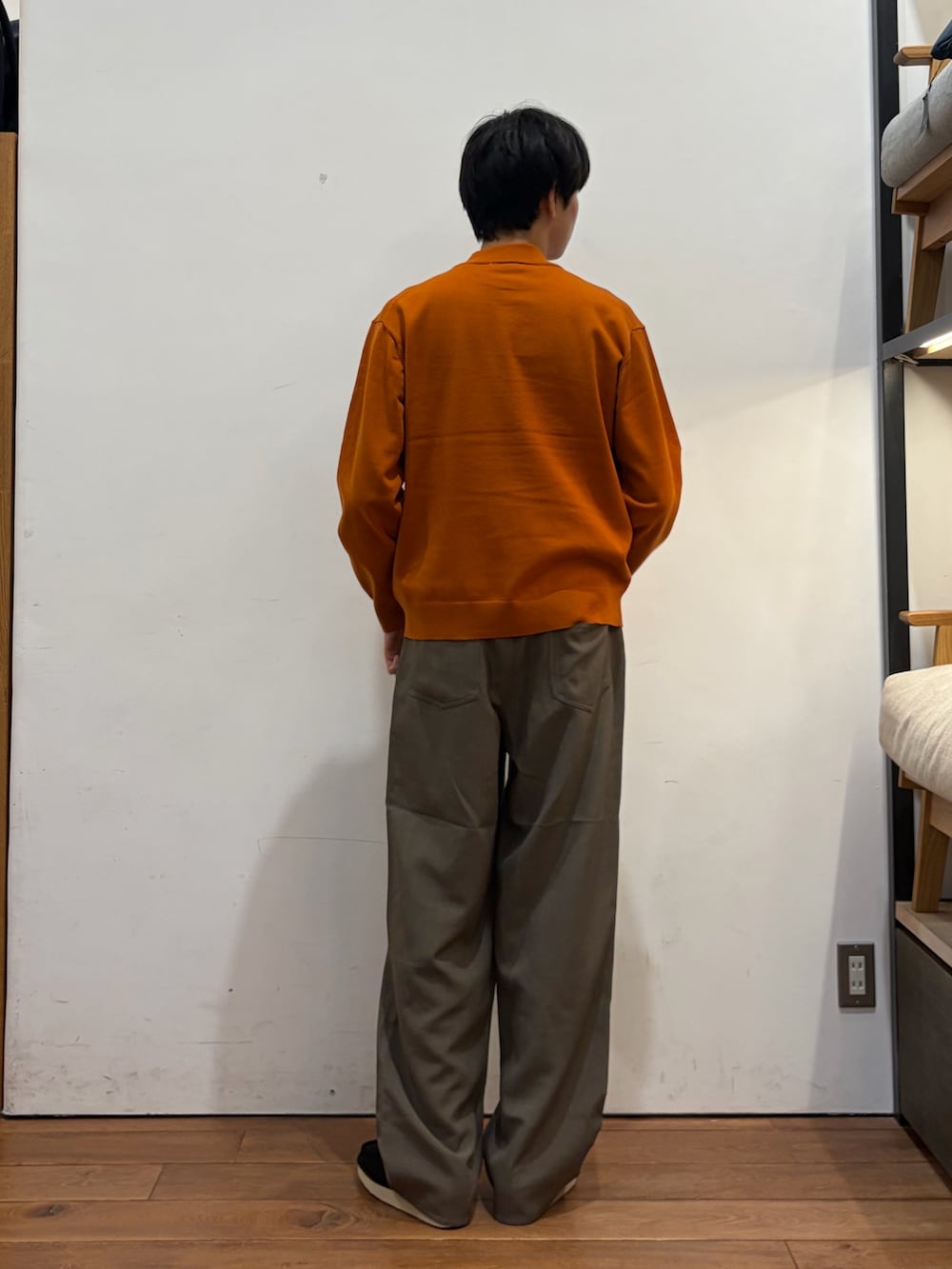 オレンジ系のニット/セーター、ベージュ系のその他パンツ、ブラック系のブーツを着用したメンズの秋コーディネートの2枚目の写真