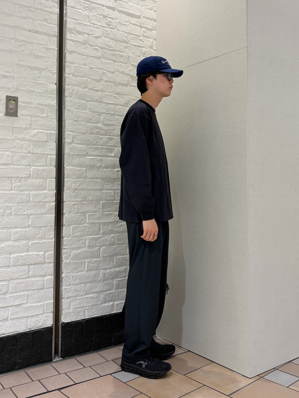 グレー系のTシャツ/カットソー、ブラック系のショルダーバッグ、ブラック系のスニーカーを着用したメンズの春コーディネートの5枚目の写真