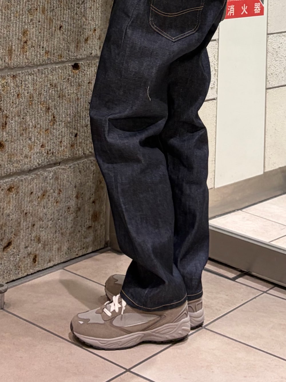 グリーン系のTシャツ/カットソー、ブルー系のデニムパンツ、ホワイト系のショルダーバッグを着用したメンズの冬コーディネートの3枚目の写真