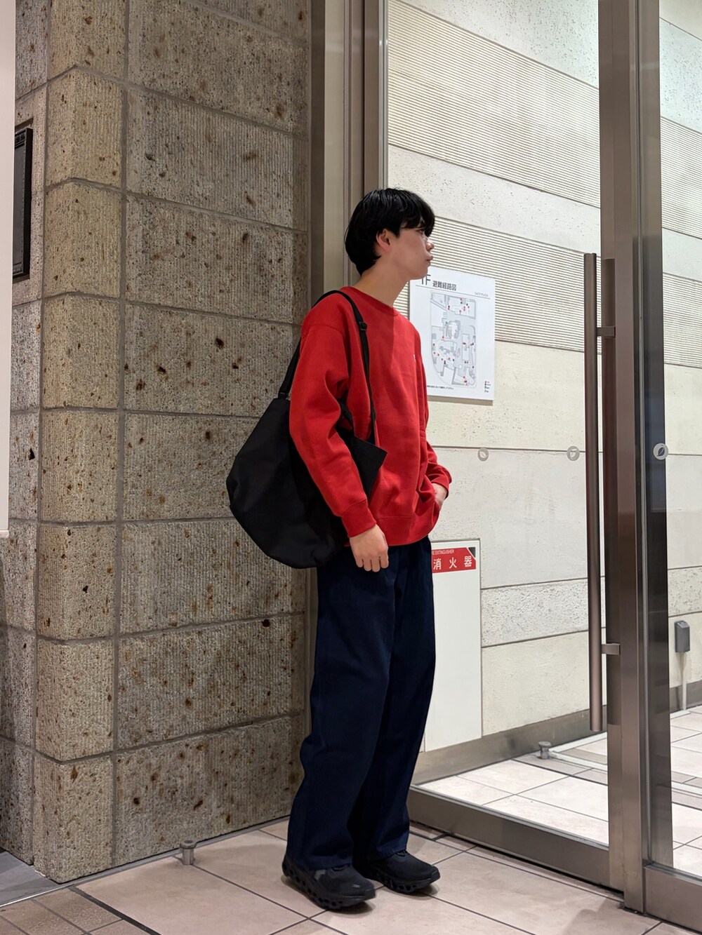 レッド系のスウェット、ブラック系のショルダーバッグ、ブルー系のデニムパンツを着用したメンズの冬コーディネートの3枚目の写真