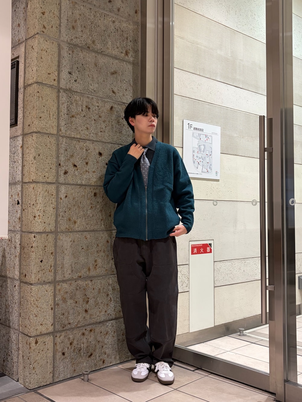 グリーン系のポロシャツ、グリーン系のカーディガン/ボレロ、グレー系のネクタイを着用したメンズの冬コーディネートの2枚目の写真