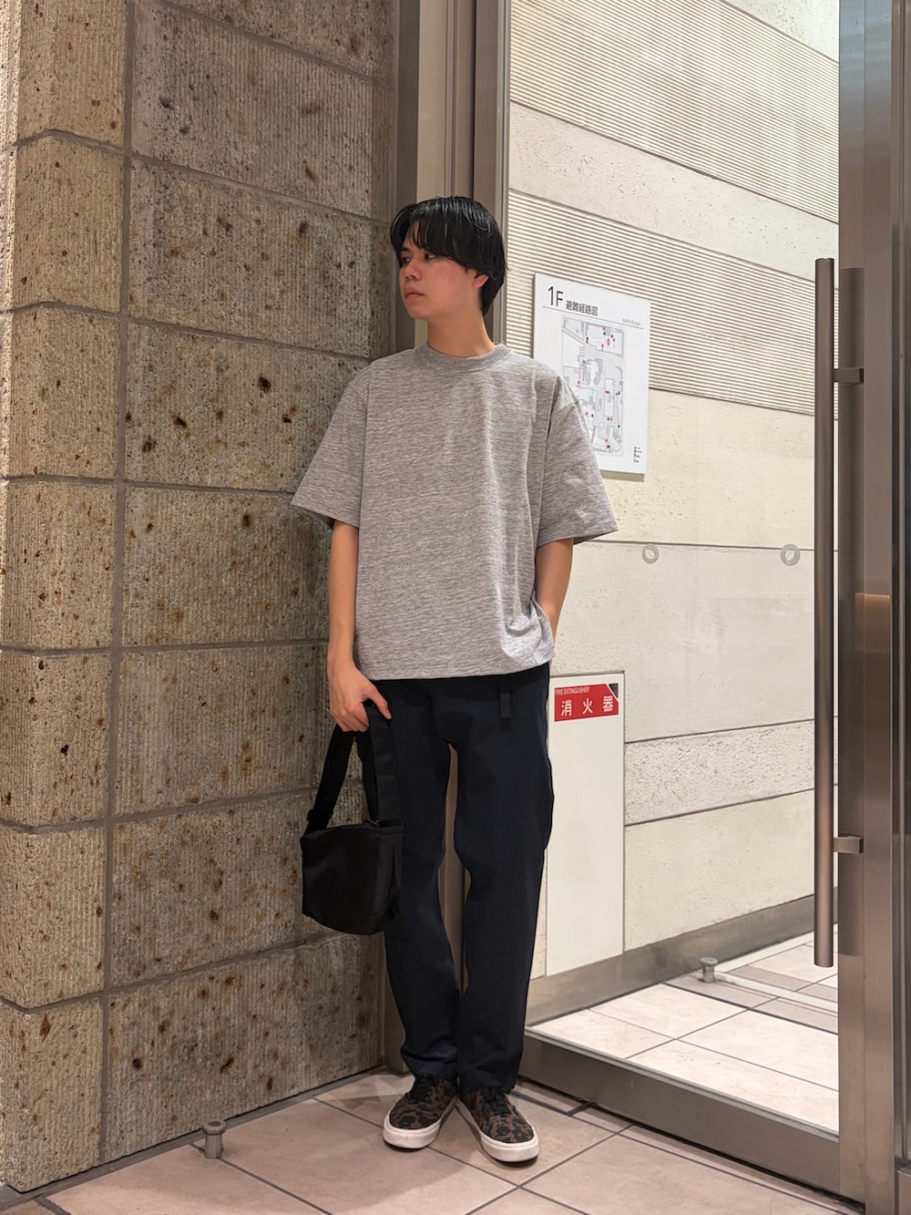 ブラウン系のスニーカー、ブラック系のショルダーバッグ、グレー系のTシャツ/カットソーを着用したメンズの春コーディネートの2枚目の写真