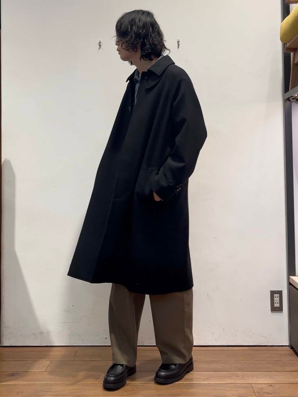 ベージュ系のTシャツ/カットソー、ブラック系のステンカラーコート、グリーン系のその他パンツを着用したメンズの冬コーディネートの3枚目の写真