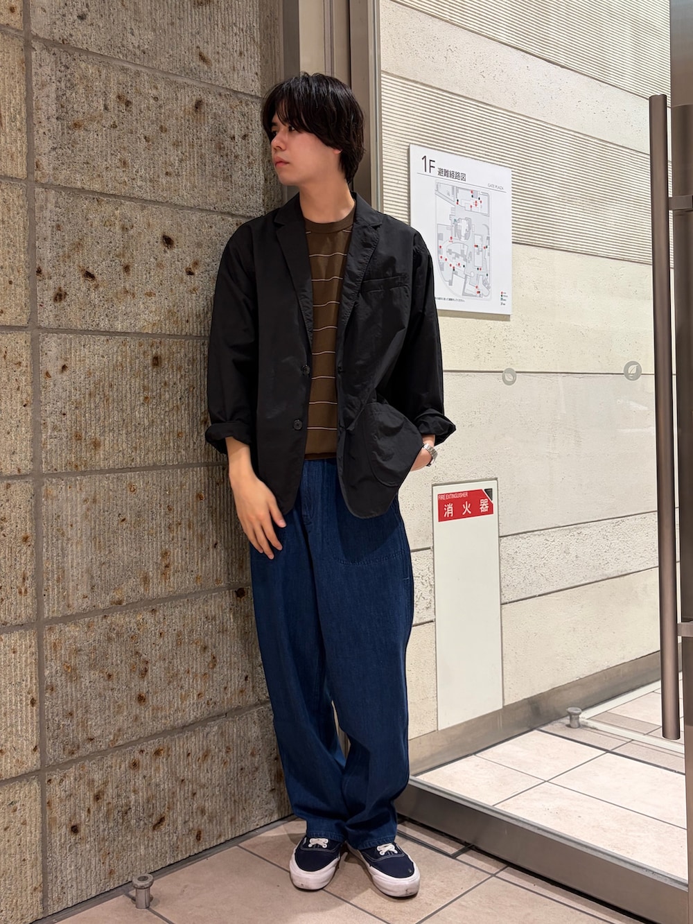 ブラック系のその他アウター、ブラウン系のニット/セーター、ブルー系のデニムパンツを着用したメンズの春コーディネートの2枚目の写真