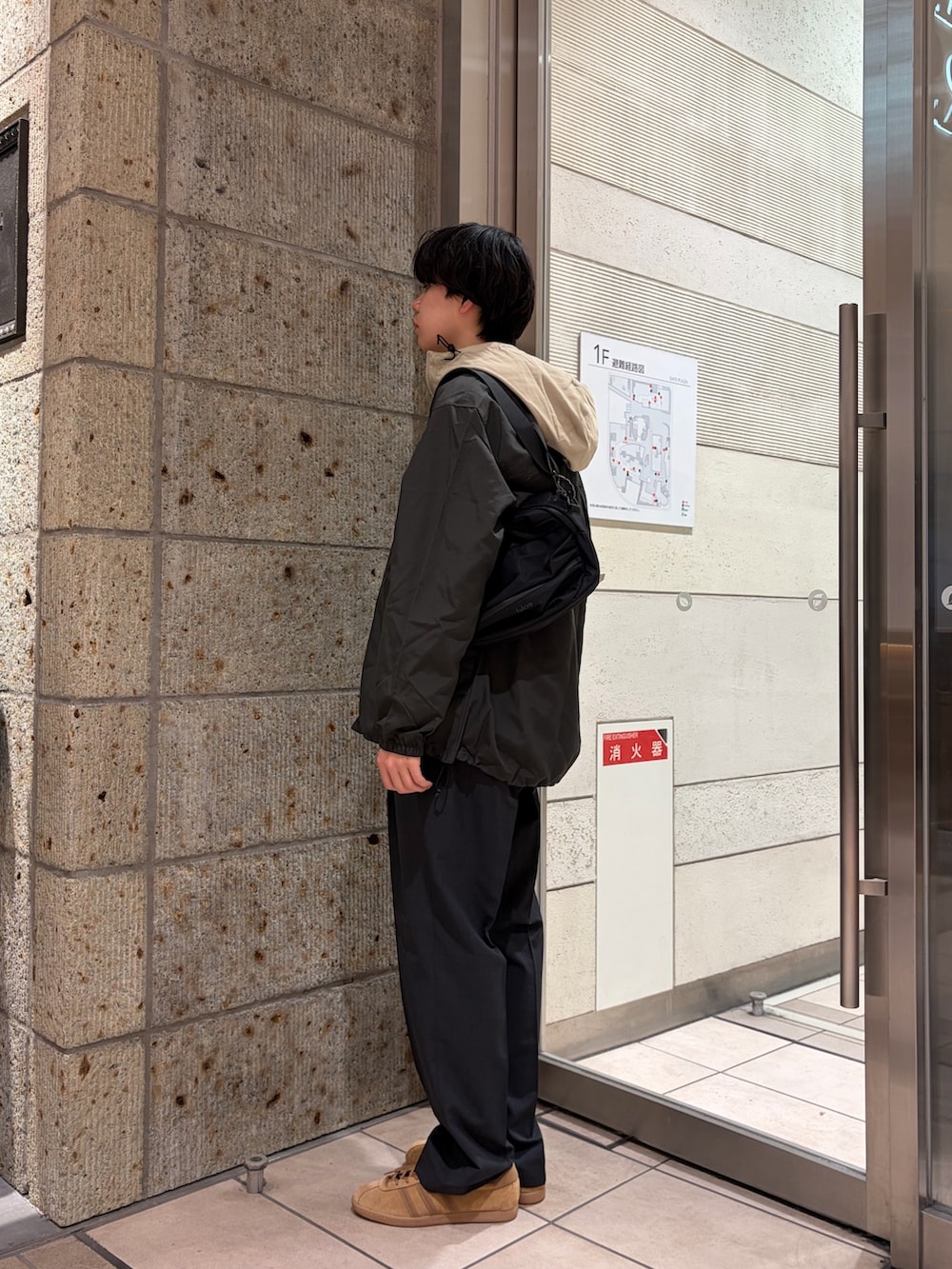 ベージュ系のマウンテンパーカー、ブラック系のその他アウター、ホワイト系のTシャツ/カットソーを着用したメンズの春コーディネートの3枚目の写真