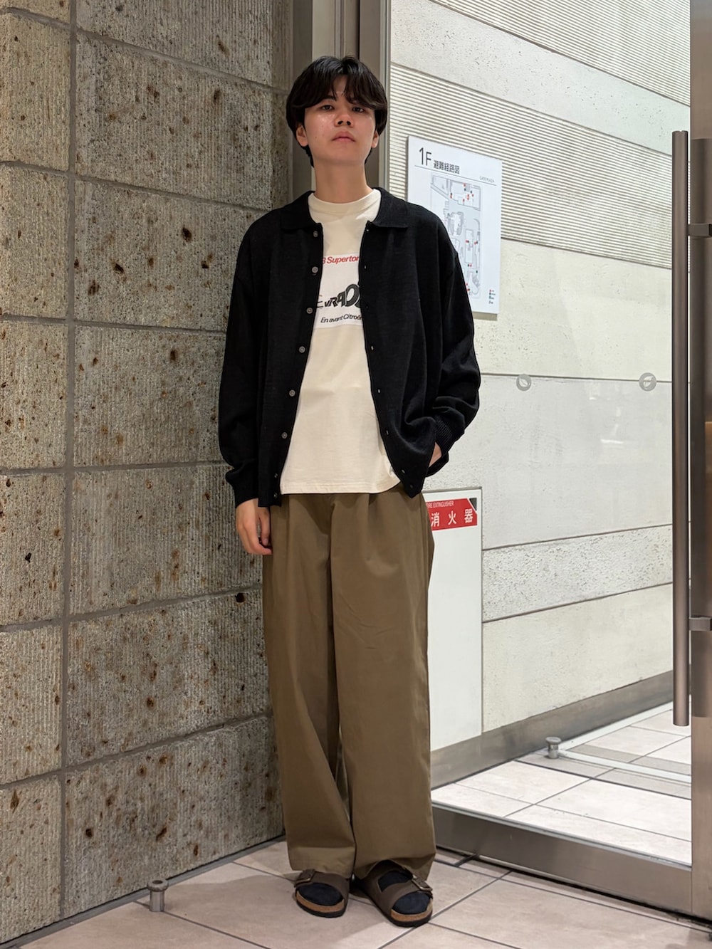 ブラック系のカーディガン/ボレロ、ホワイト系のTシャツ/カットソー、ベージュ系のチノパンツを着用したメンズの夏コーディネートの2枚目の写真