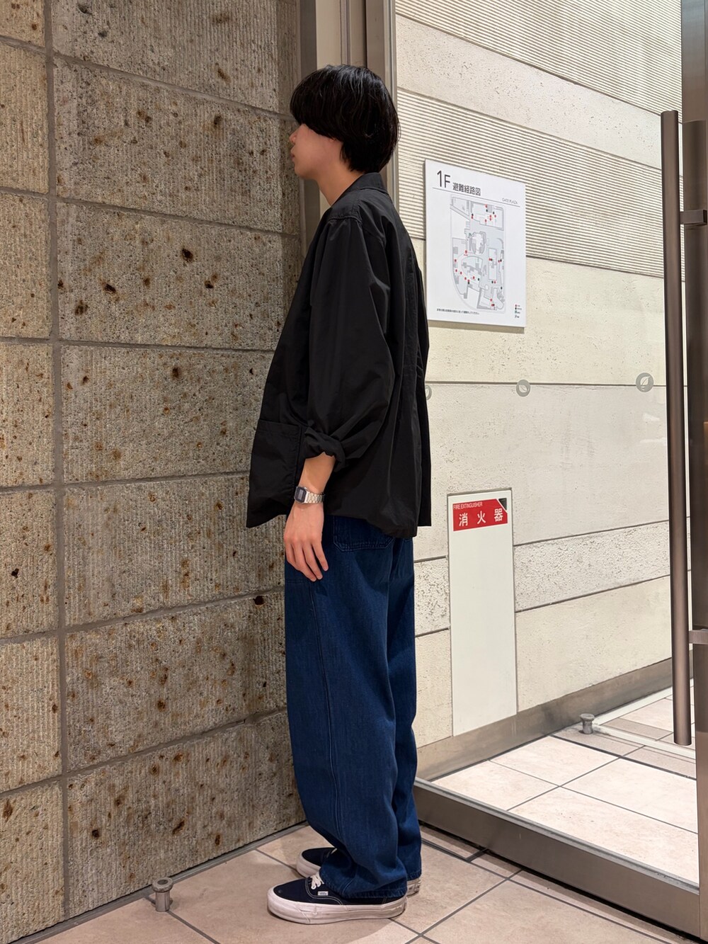 ブラック系のその他アウター、ブラウン系のニット/セーター、ブルー系のデニムパンツを着用したメンズの春コーディネートの4枚目の写真