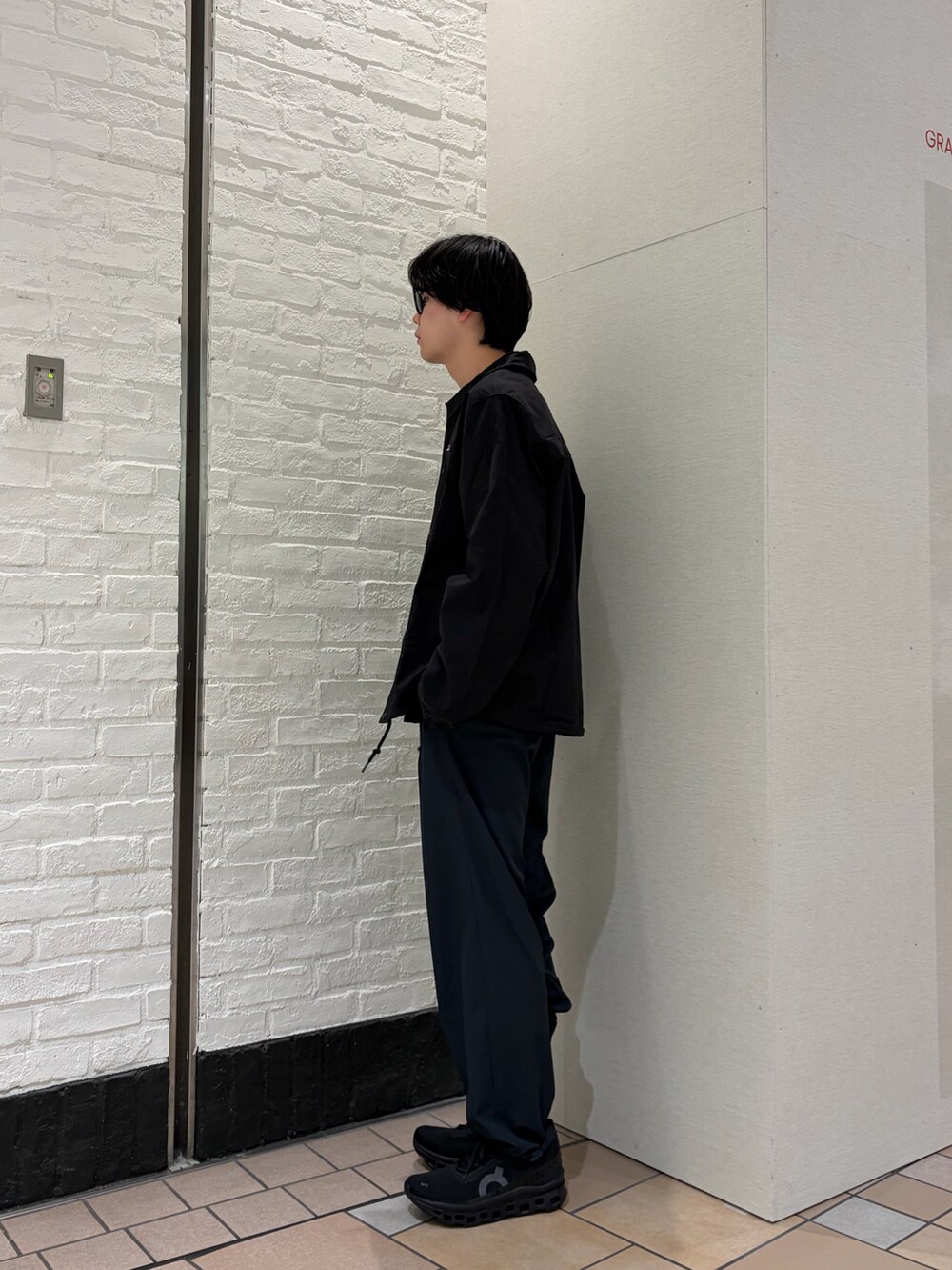 ブラック系のカバーオール、ブルー系のTシャツ/カットソー、ブラック系のスニーカーを着用したメンズの春コーディネートの3枚目の写真
