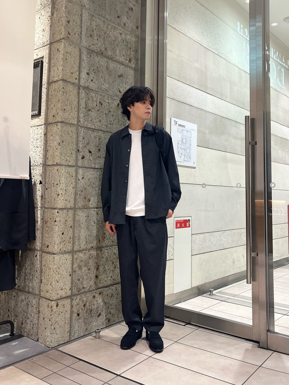 ブラック系のビジネスバッグ、グレー系のTシャツ/カットソー、ブラック系のドレスシューズを着用したメンズの秋コーディネートの2枚目の写真