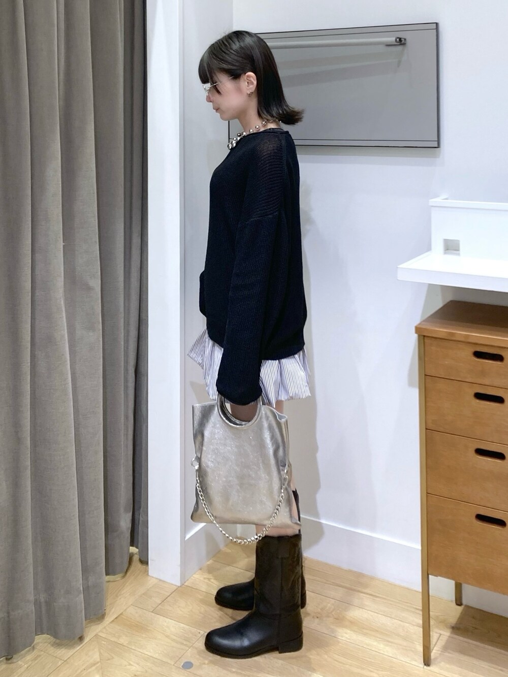 ブルー系のスカート、シルバー系のショルダーバッグ、ブラック系のブーツを着用したレディースの春コーディネートの2枚目の写真