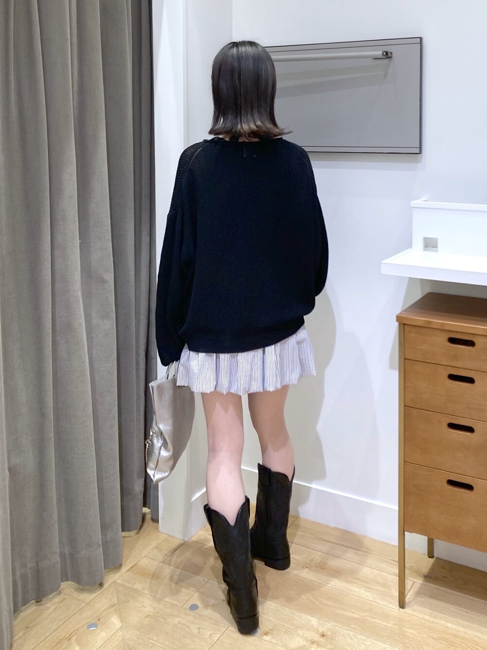 ブルー系のスカート、シルバー系のショルダーバッグ、ブラック系のブーツを着用したレディースの春コーディネートの3枚目の写真