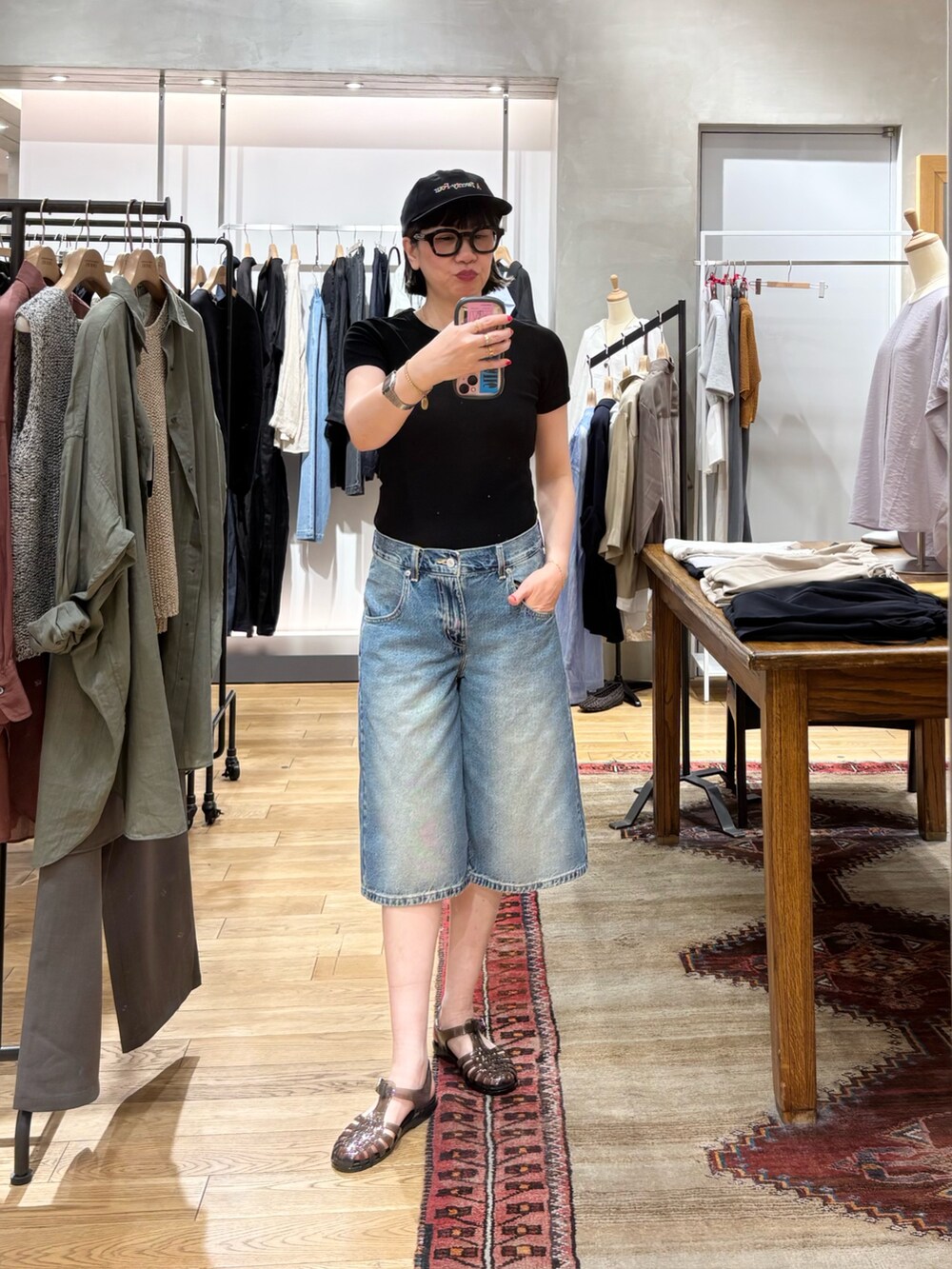 ブラック系のTシャツ/カットソー、オレンジ系のトートバッグ、ブルー系のデニムパンツを着用したレディースの春コーディネートの4枚目の写真