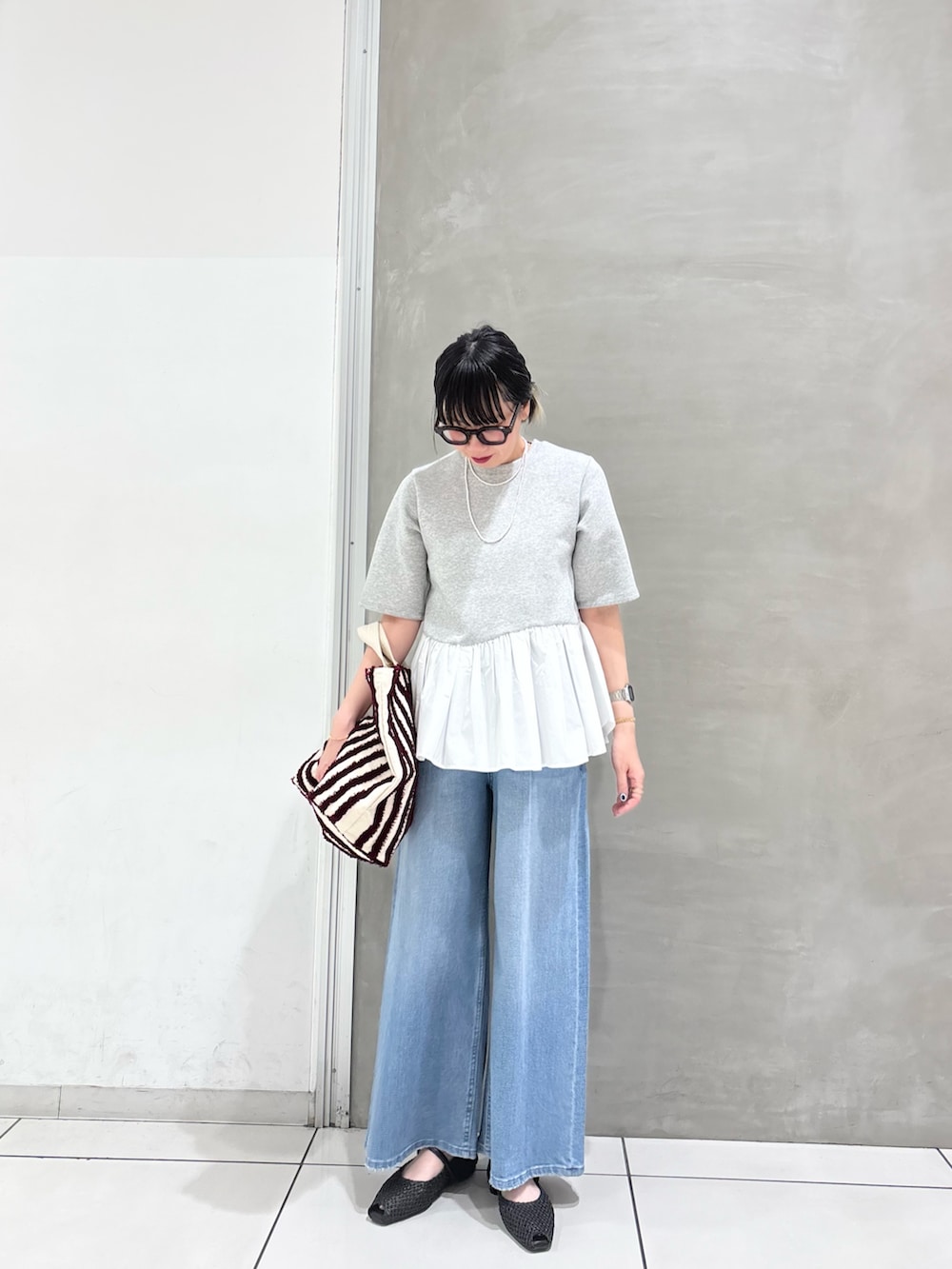 グレー系のTシャツ/カットソー、ブラウン系のバッグ、ブルー系のデニムパンツを着用したレディースの春コーディネートの4枚目の写真