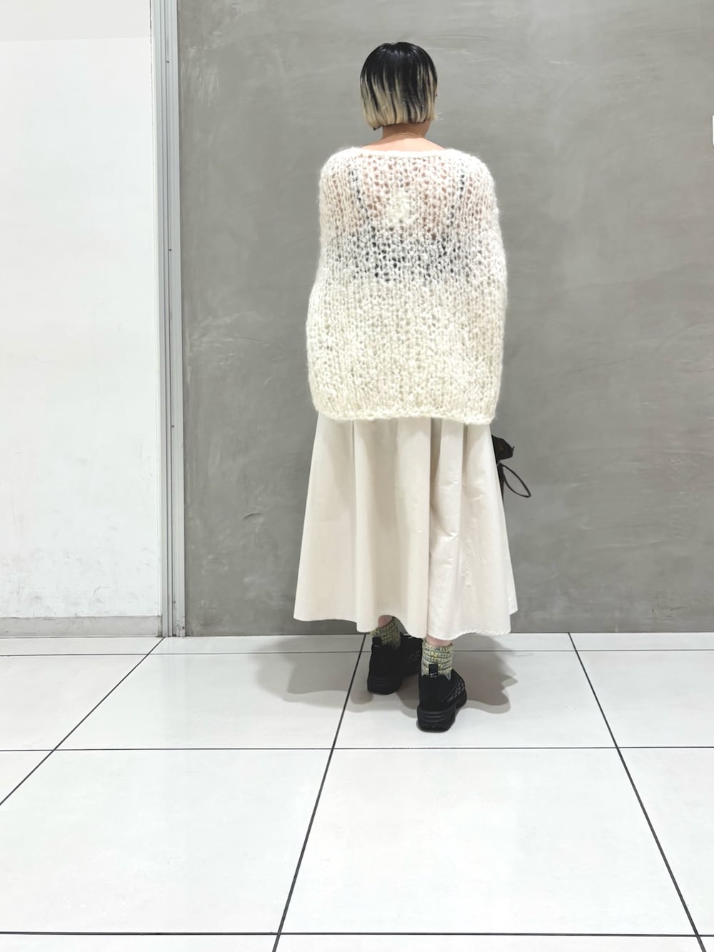 ホワイト系のニット/セーター、ホワイト系のスカート、ブラウン系のショルダーバッグを着用したレディースの秋コーディネートの3枚目の写真